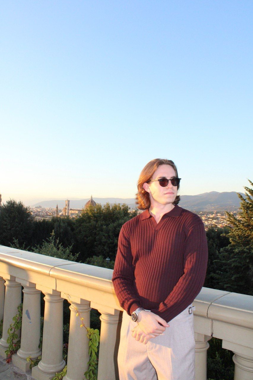 Denis Maksimov in sunglasses on a terrace above a city at sunset
